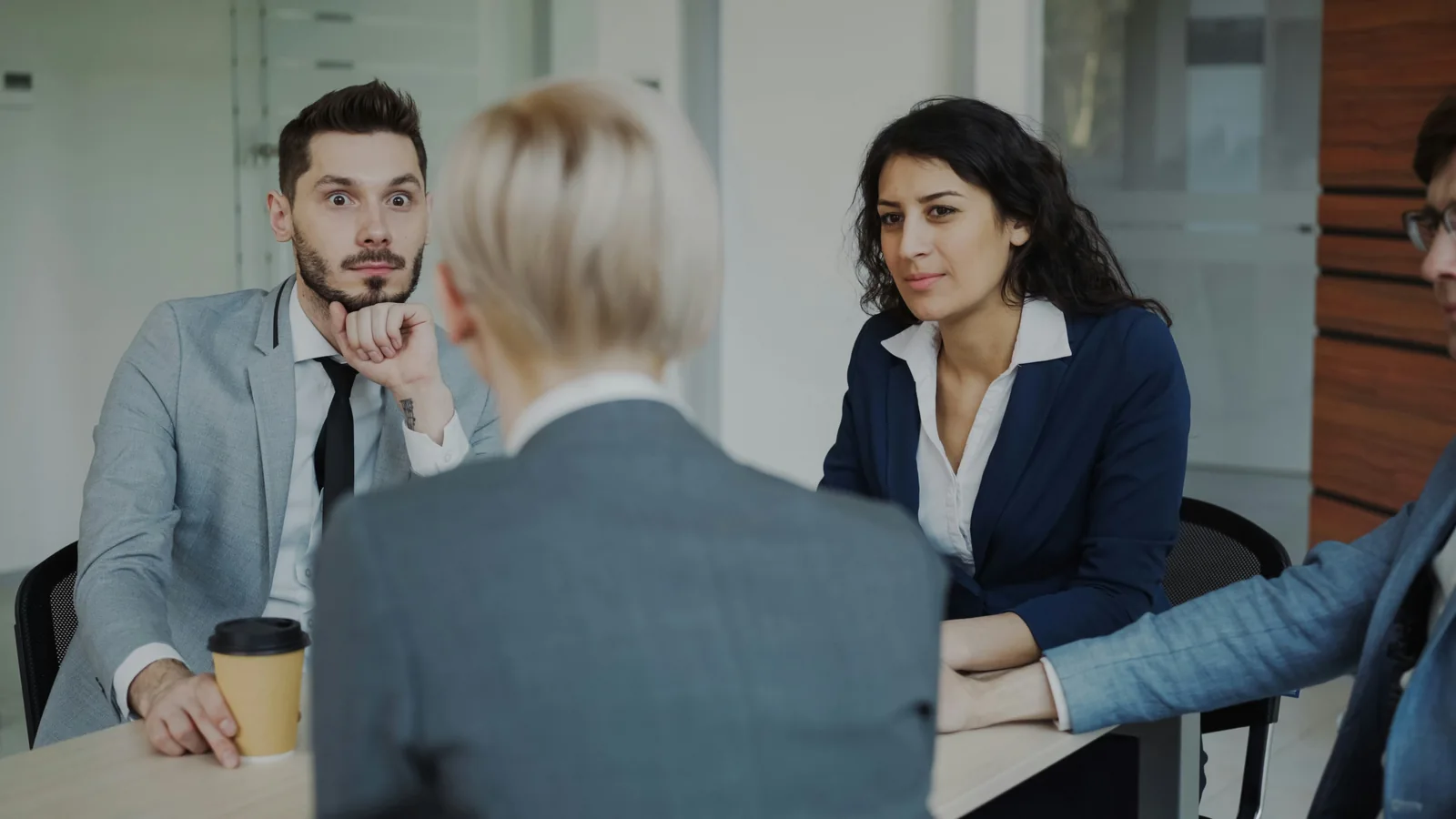 A group of professionals in a focused discussion around an office table.