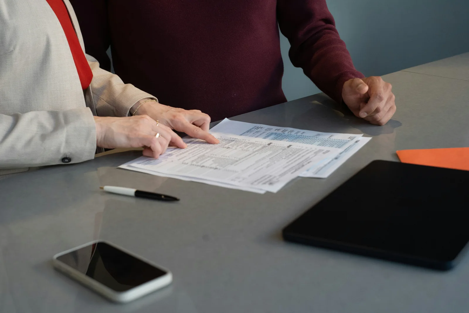 Hands examining documents together at a conference table.